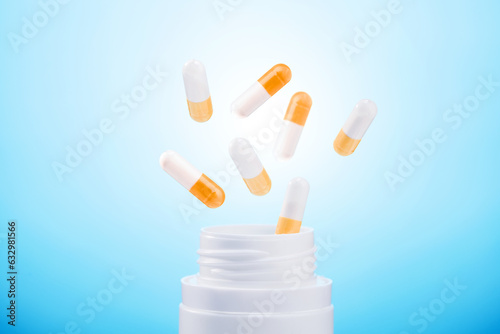  pills from plastic medicine bottle on blue background. group of antibiotic pill capsules fallling.