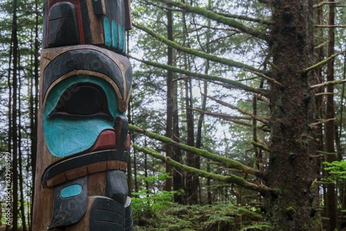 Tlingit totem poles and lush woods tree nature landscape scenery in Sitka Historical Park hiking trails with creeks, green bushes and vegetation in magic fairytale environment Baranof Island photo