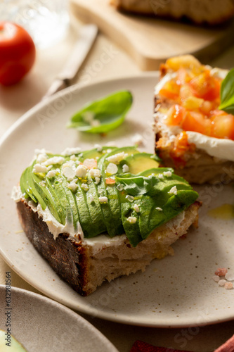 Avocado and salmon toasts with sourdough bread, sliced avocado, cream cheese and basil