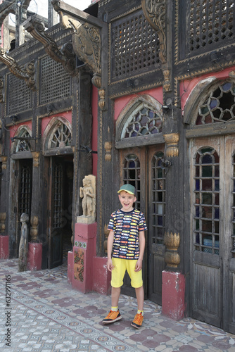 Ancient architecture, old building facade, house and tourist child, cute boy, kid in Lahore, Pakistan. Lahore landmark, old monument, interior. Wooden architecture. Cooco's den cafe, old restaurant © Sergey