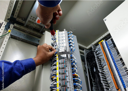 The electrical technician replacing the auxiliary relay in the control cubicle.