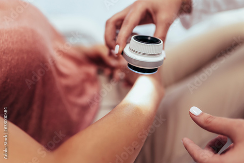 The dermatologist examines the moles or acne of the patient with a dermatoscope. Prevention of melanoma photo