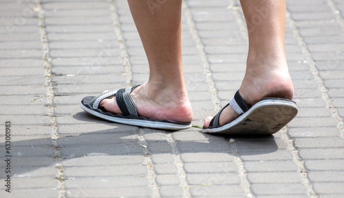 Legs of a man in flip flops on paving slabs