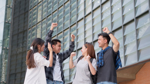Group of happy young entrepreneurs with hands up and laughing to celebrate and excited success for achievements obtained. Undergraduate students celebrate success after end project, teamwork concept