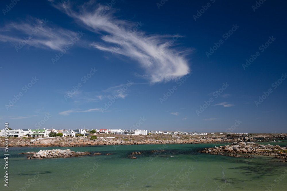 Houses on a rocky shore with beautiful white clouds in a blue sky