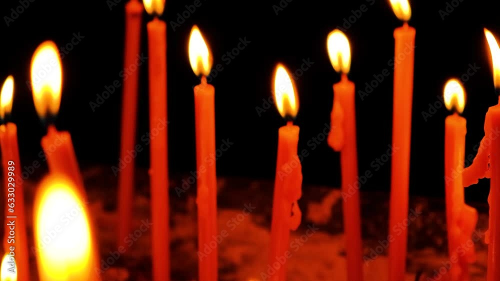A lot of burning candles in the temple in the dark. The concept of religion, prayer and God. A lot of burning candles in the temple in the dark. The concept of religion, prayer and God.