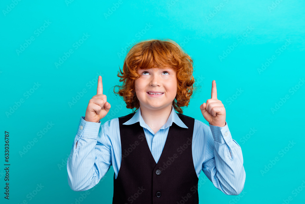 Photo portrait of adorable foxy wavy hair boy look up empty space wear trendy school uniform outfit isolated on aquamarine color background Photo portrait of adorable foxy wavy hair boy look up empty space wear trendy school uniform outfit isolated on aquamarine color background