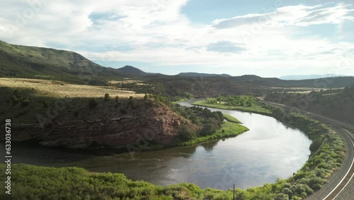 Back away from Colorado River by train tracks under red rock dry desert mesas in summer