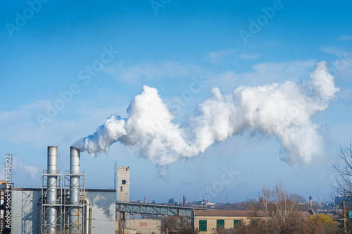 Chimney stalk with smoke on blue sky background. Environmental pollution