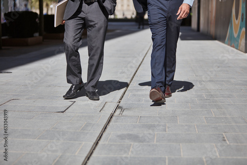 Legs of businessmen walking on sidewalk photo