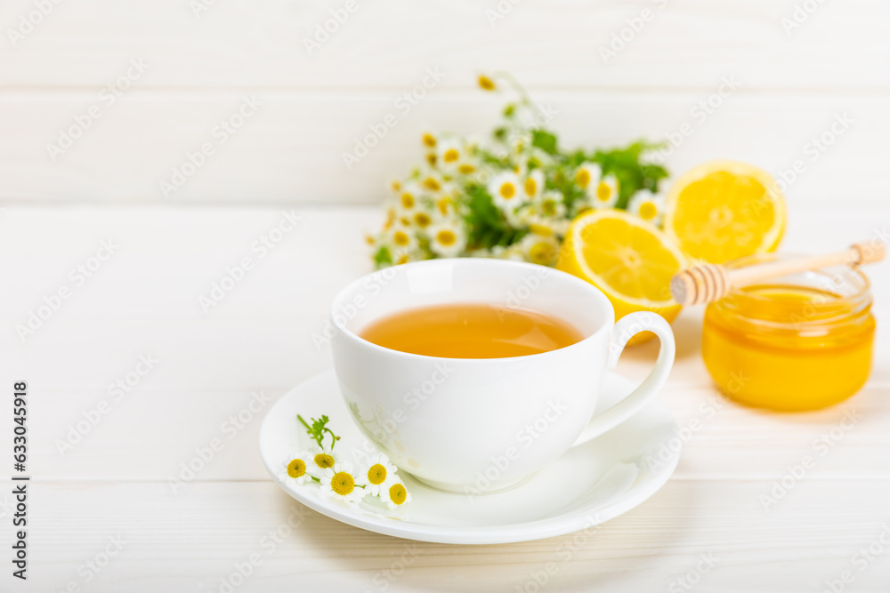 Chamomile tea on a white table. Delicious tonic, soothing and relaxing chamomile tea with chamomile flowers, honey and lemon. Herbal tea for immunity. Close-up.Place for text.Copy space. Chamomile tea on a white table. Delicious tonic, soothing and relaxing chamomile tea with chamomile flowers, honey and lemon. Herbal tea for immunity. Close-up.Place for text.Copy space.