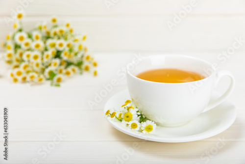 Chamomile tea on a white table. Delicious tonic  soothing and relaxing chamomile tea with chamomile flowers  honey and lemon. Herbal tea for immunity. Close-up.Place for text.Copy space.