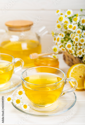 Chamomile tea on a white table. Delicious tonic, soothing and relaxing chamomile tea with chamomile flowers, honey and lemon. Herbal tea for immunity. Close-up.Place for text.Copy space.