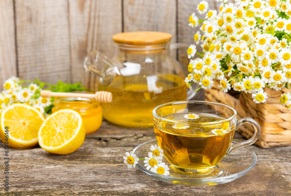 Chamomile tea on a brown table. Delicious tonic, soothing and relaxing chamomile tea with chamomile flowers, honey and lemon. Herbal tea for immunity. Close-up.Place for text.Copy space.