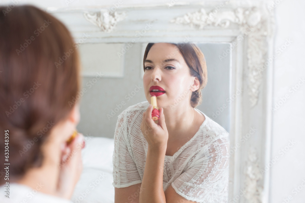 Mid adult woman applying make-up in mirror. Mid adult woman applying make-up in mirror.