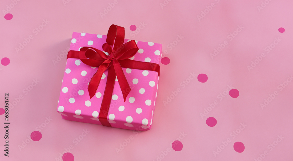 Fototapeta premium pink gift box with white dots with pink ribbon on pastel pink background in high resolution and sharpness