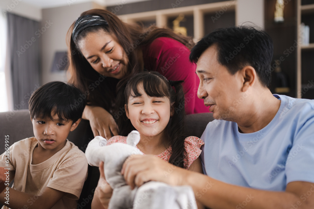 Asian family with father and mother in Father's Day concept, happy daddy and young children having smile and fun together at home, childhood care relationships lifestyle in a house living room