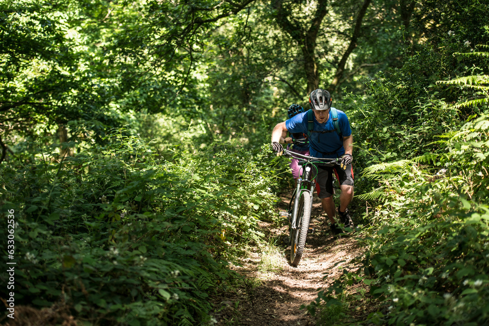 Man pushing mountain bike uphill in Porlock Weir, England Man pushing mountain bike uphill in Porlock Weir, England
