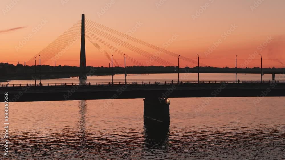 Beautiful aerial view of Riga city - the capital of Latvia. Magical sunset over the suspension bridge in Riga with public transport passing the bridge. Beautiful aerial view of Riga city - the capital of Latvia. Magical sunset over the suspension bridge in Riga with public transport passing the bridge.