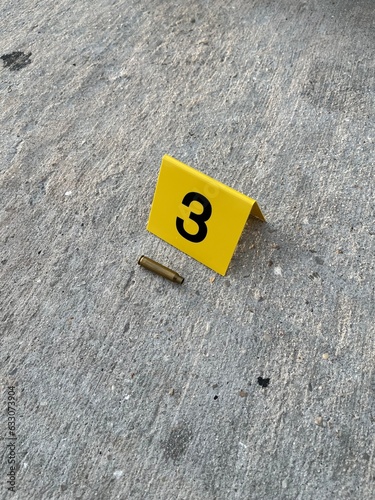 One yellow crime scene evidence marker on the street after a gun shooting brass bullet shell casing rifle