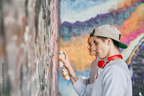 Teenage boys spray painting on wall photo