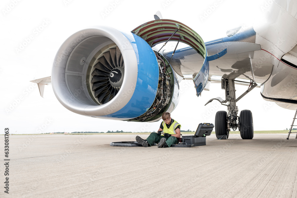 Man working on airplane engine on runway Man working on airplane engine on runway
