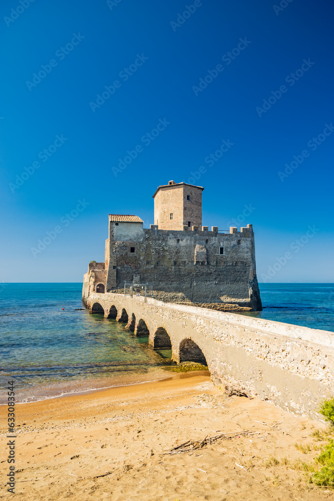 The Torre Astura nature reserve, in Nettuno. The ancient castle on the sea, with the watchtower and the remains of ancient Roman buildings. A stone bridge connects the castle to the beach.