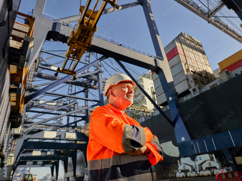 Low angle view of dock worker beneath cranes at Port of Felixstowe, England Low angle view of dock worker beneath cranes at Port of Felixstowe, England