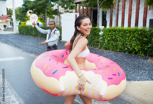 Young woman walking along street with doughnut pool toy photo