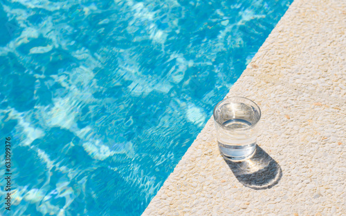 a glass of clean drinking water near the pool on a hot day. Summer vacation concept © Nikita