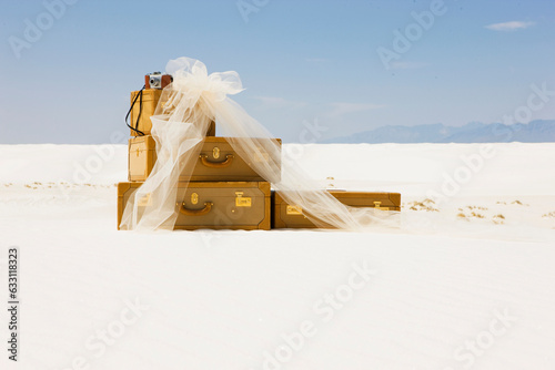 suitcases, a vintage camera and sheer material on the sand in the desert.