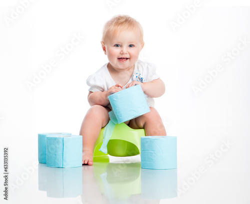 little baby sitting on a pot and keeps the toilet paper. studio photo on white background