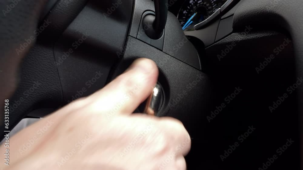 Starting a car engine. Hand of driver inserts car key into ignition