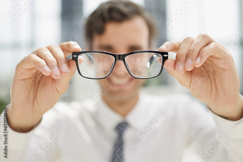 a young man sits at a table and looks at the camera through glasses