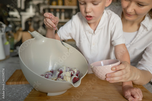 Boy an mam mixing condensed milk and strawberry in bowl