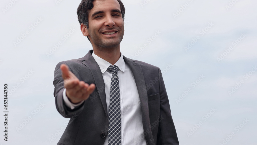 Modern businessman smiles and stretches his hand to the camera wishing to greet Modern businessman smiles and stretches his hand to the camera wishing to greet