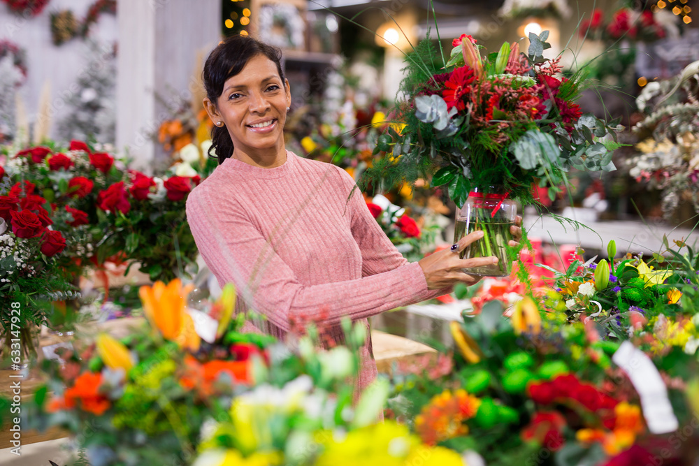 Portrait of a confident latin american woman choosing a bouquet of flowers in a store
