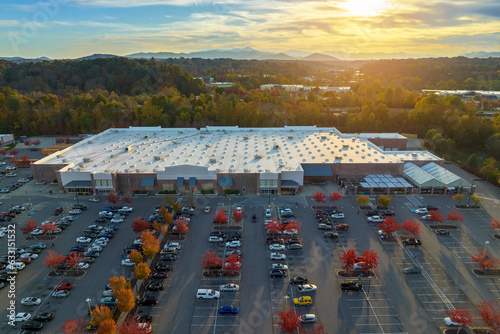Aerial view of large parking lot in front of rgocery store with many parked colorful cars. Carpark at supercenter shopping mall with lines and markings for vehicle places and directions