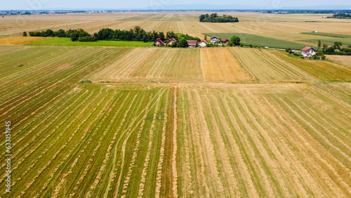 Field after harvest in summer and village in the distance, drone shot.