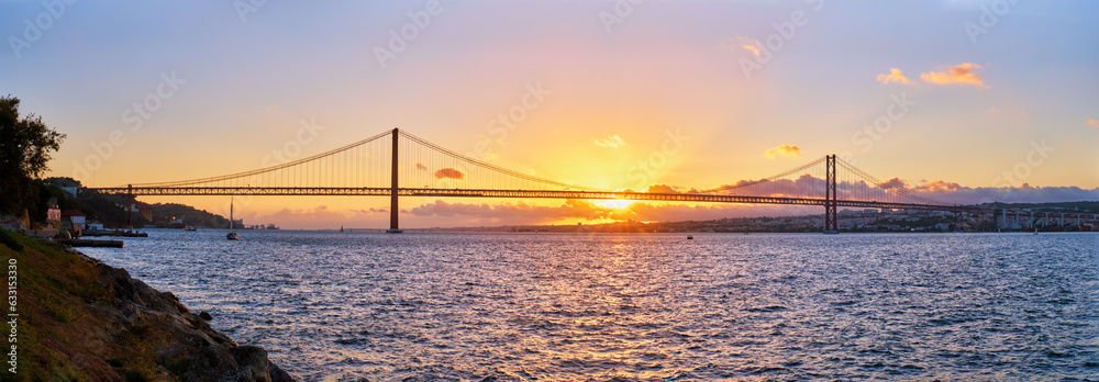 Panorama of 25 de Abril Bridge over Tagus river on sunset. Lisbon, Portugal