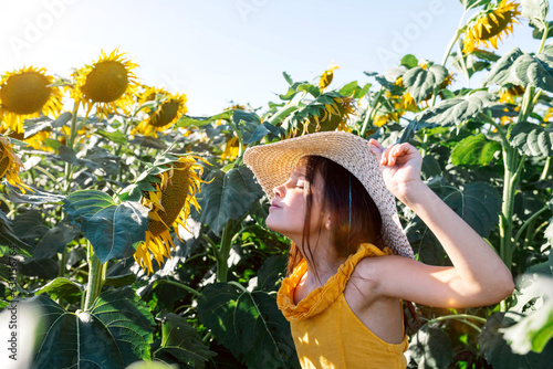 Girl with eyes closed smelling sunflower in farm photo