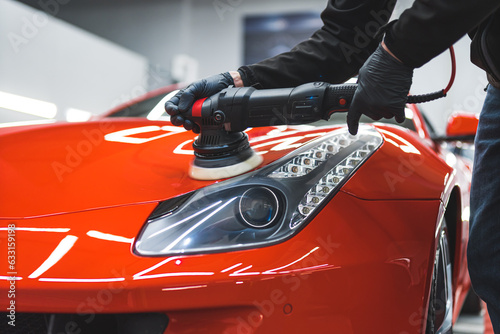 a man polishing an orange car headlight, indoors. High quality photo photo