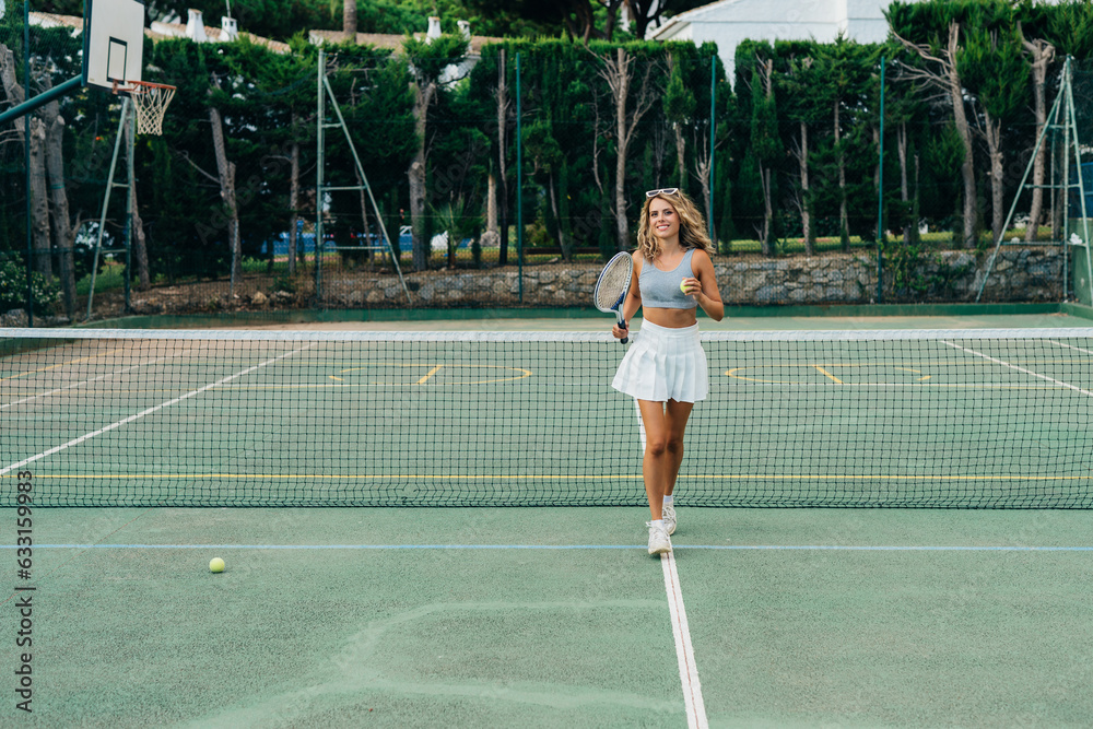 Beautiful blonde girl posing on the tennis court with a racket in her hands. fashion beauty makeup style