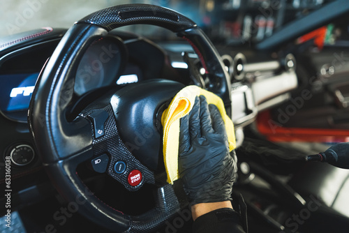 closeup shot of a specialist with gloves cleaning a steering wheel, car detailing. High quality photo © PoppyPix