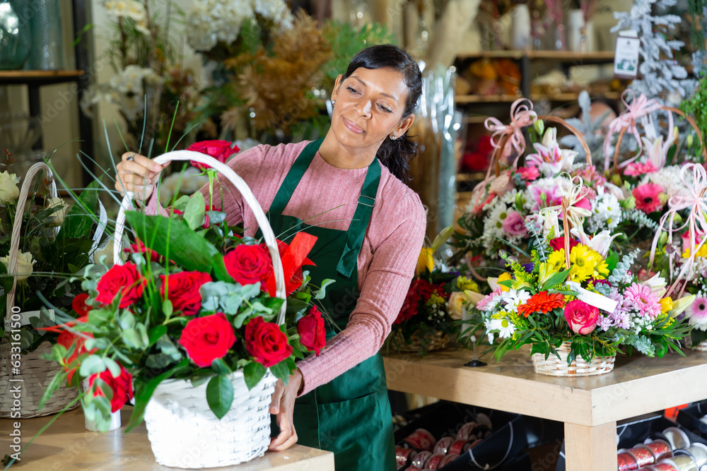 Friendly Latin American female florist working in a flower shop is preparing a chic bouquet for sale