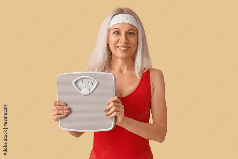 Sporty mature woman with scales on beige background