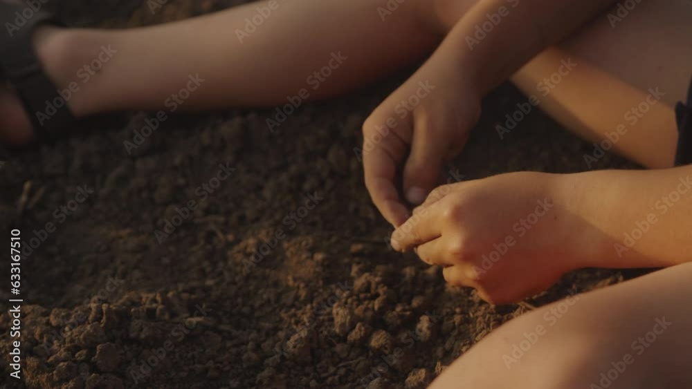 Close up of little boy's hands playing with black soil in garden while sitting. Happy earth day. Happy childhood concept. Ecology concept.