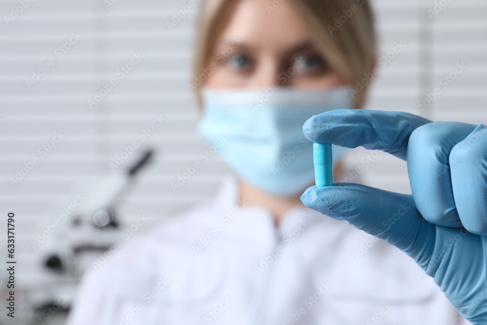 Doctor holding pill on light background, selective focus. Space for text Doctor holding pill on light background, selective focus. Space for text