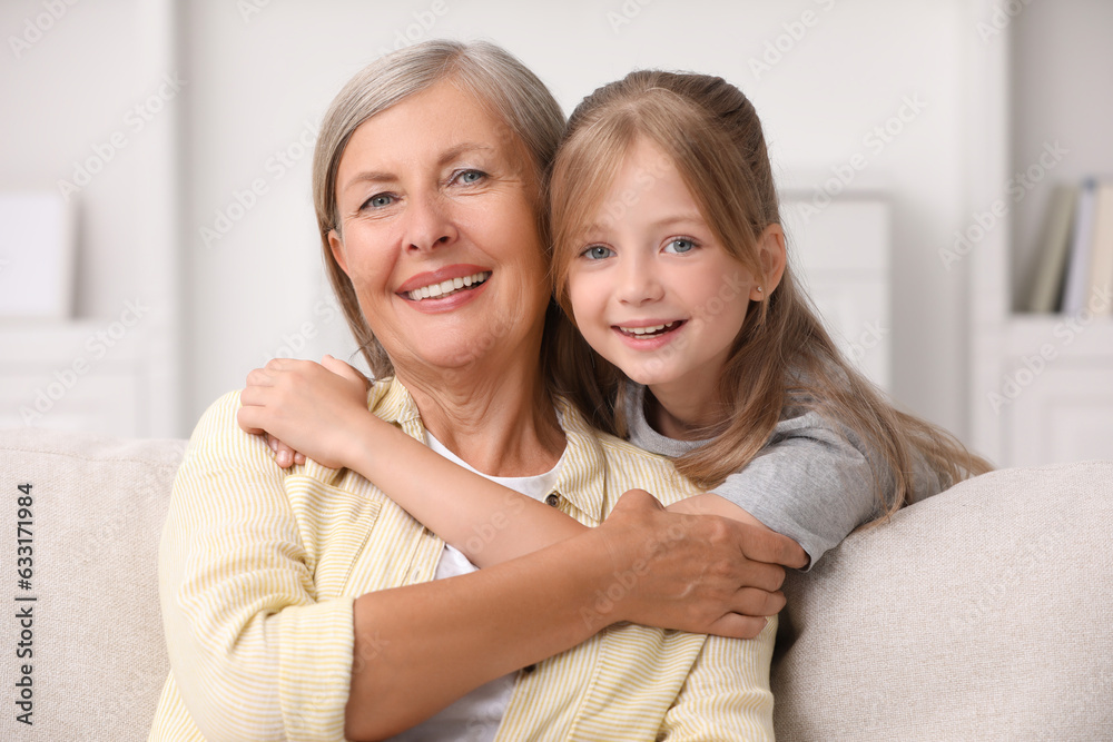 Happy grandmother hugging her granddaughter at home