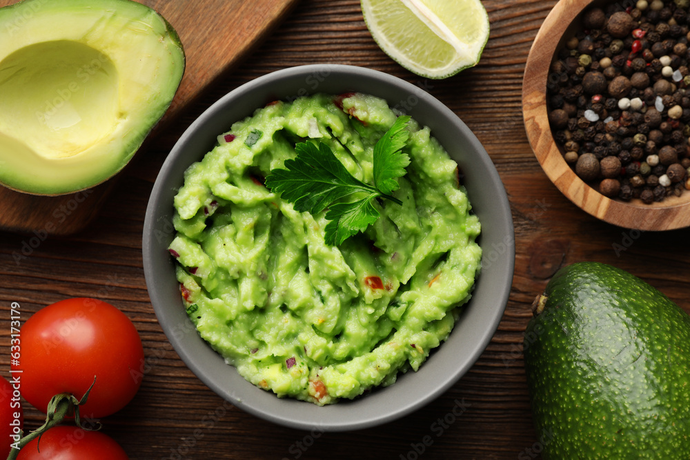 Delicious guacamole and ingredients on wooden table, flat lay Delicious guacamole and ingredients on wooden table, flat lay